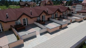A residential building with multiple balconies, a paved terrace, and a view of surrounding houses and greenery. - Apartment Eric 9D High Tatras (Velky Slavkov)