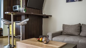 A modern living room with a wooden coffee table, a grey sofa, and a TV mounted on a wooden wall. - Apartment Eric 9D High Tatras (Velky Slavkov)
