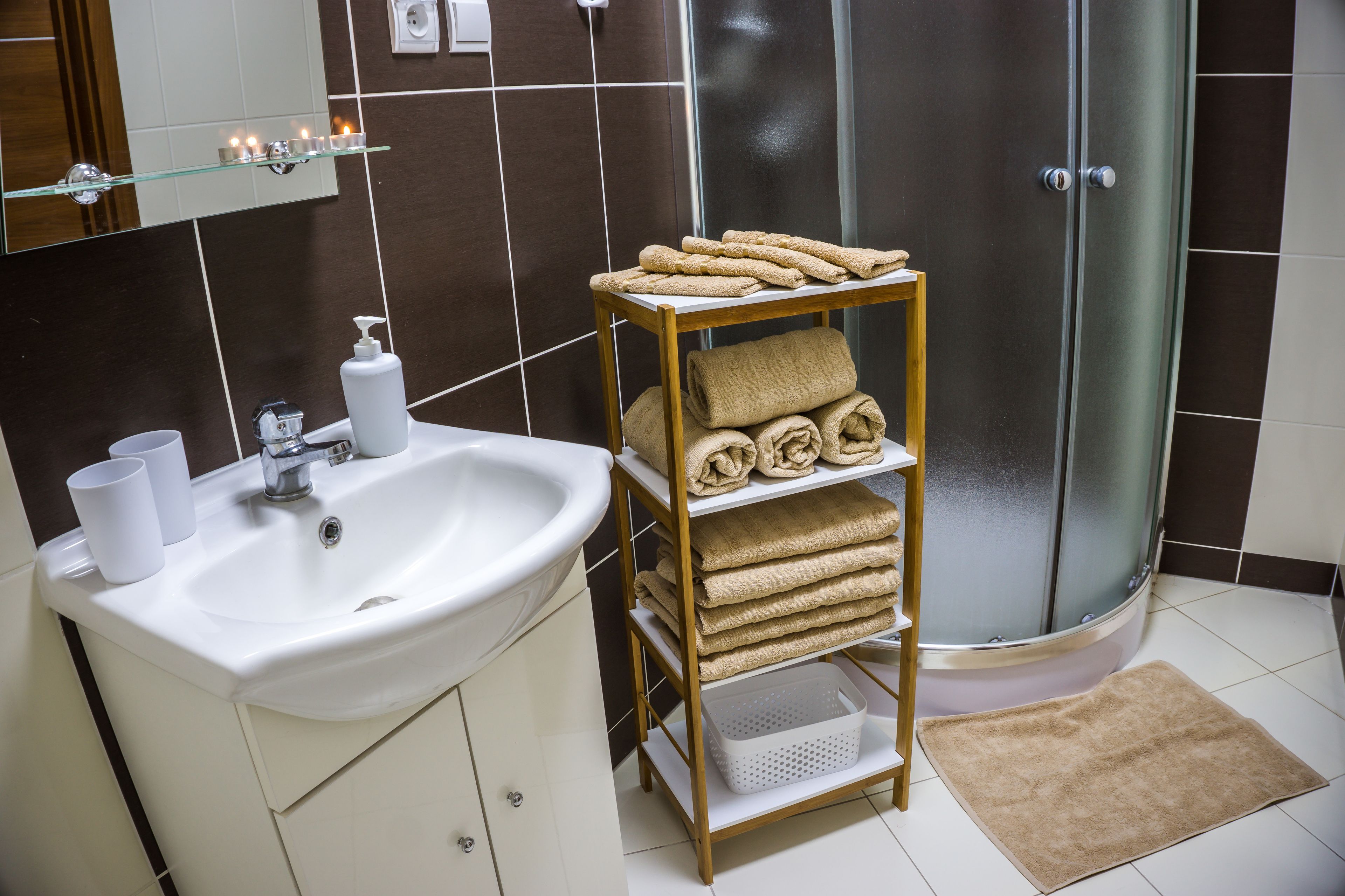 A bathroom with a sink, mirror, towel rack, and shower.