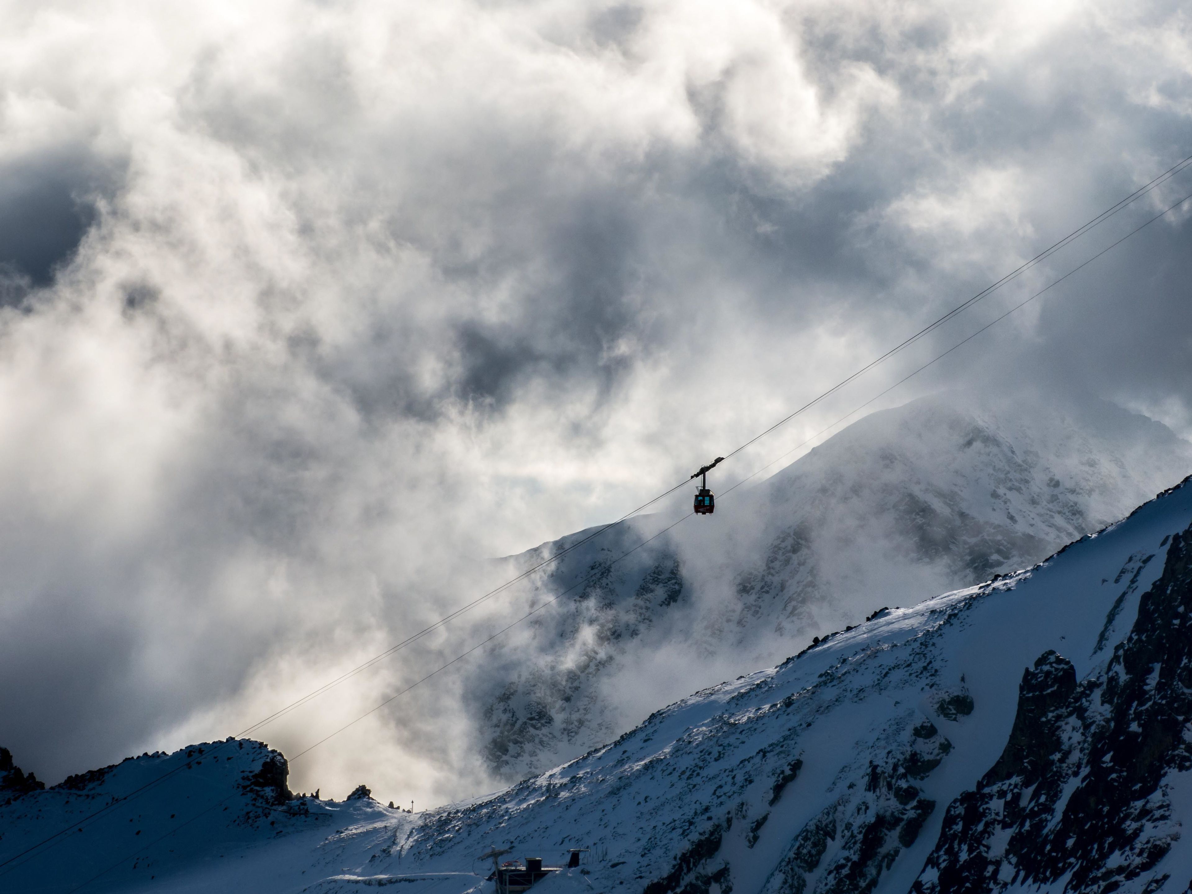 A cable car moving along a snowy mountain slope.