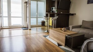 A modern living room with a wooden coffee table, a grey sofa, and a flat-screen TV mounted on the wall. - Apartment Eric 9D High Tatras (Velky Slavkov)