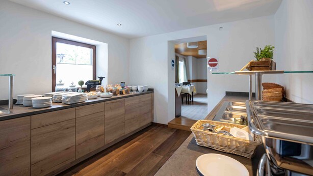 A modern kitchen with a breakfast bar, wooden cabinets, and a window.