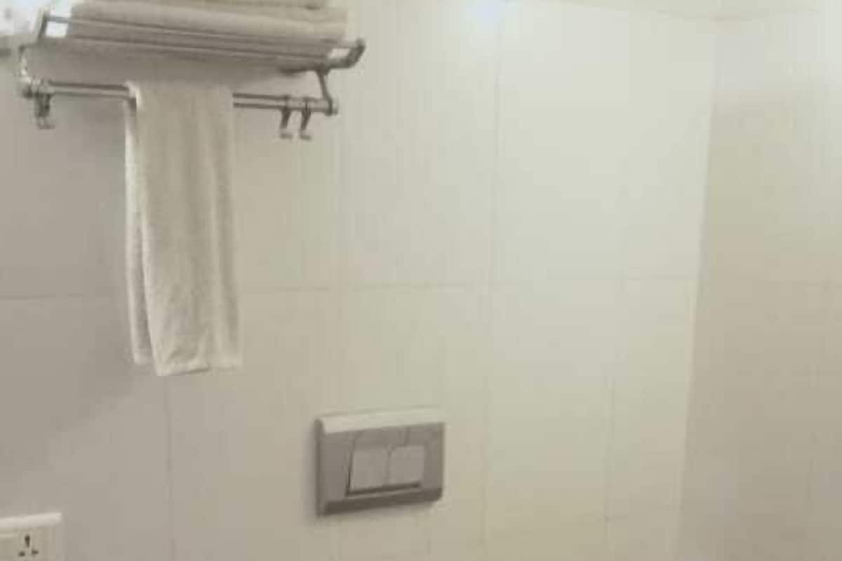 Une salle de bain équipée de toilettes, d’un porte-serviettes, d’un support à papier toilette et d’un interrupteur au mur.