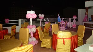 Uma sala de banquetes com mesas e cadeiras cobertas em dourado e vermelho.