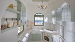A kitchen with a built-in oven, a Bosch refrigerator, and a window with a view of the sea. - Archon Villa by K&K (Oia)