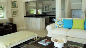 Ein Wohnzimmer mit einer Couch, einem Couchtisch und einem Bett. Durch einen offenen Durchgang ist eine Küche erkennbar.