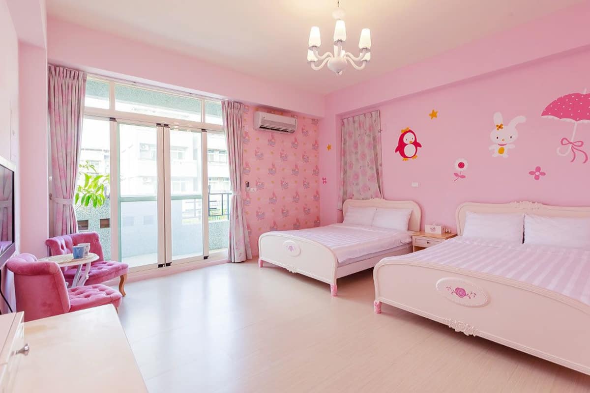 A pink-themed bedroom with two beds, a TV, and a balcony view.