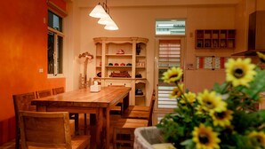Un comedor con una mesa y sillas de madera, una estantería con juguetes, y una ventana con vistas.