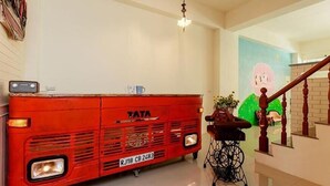 Un coche Tata rojo antiguo estacionado en una habitación con una escalera y un mural en la pared.