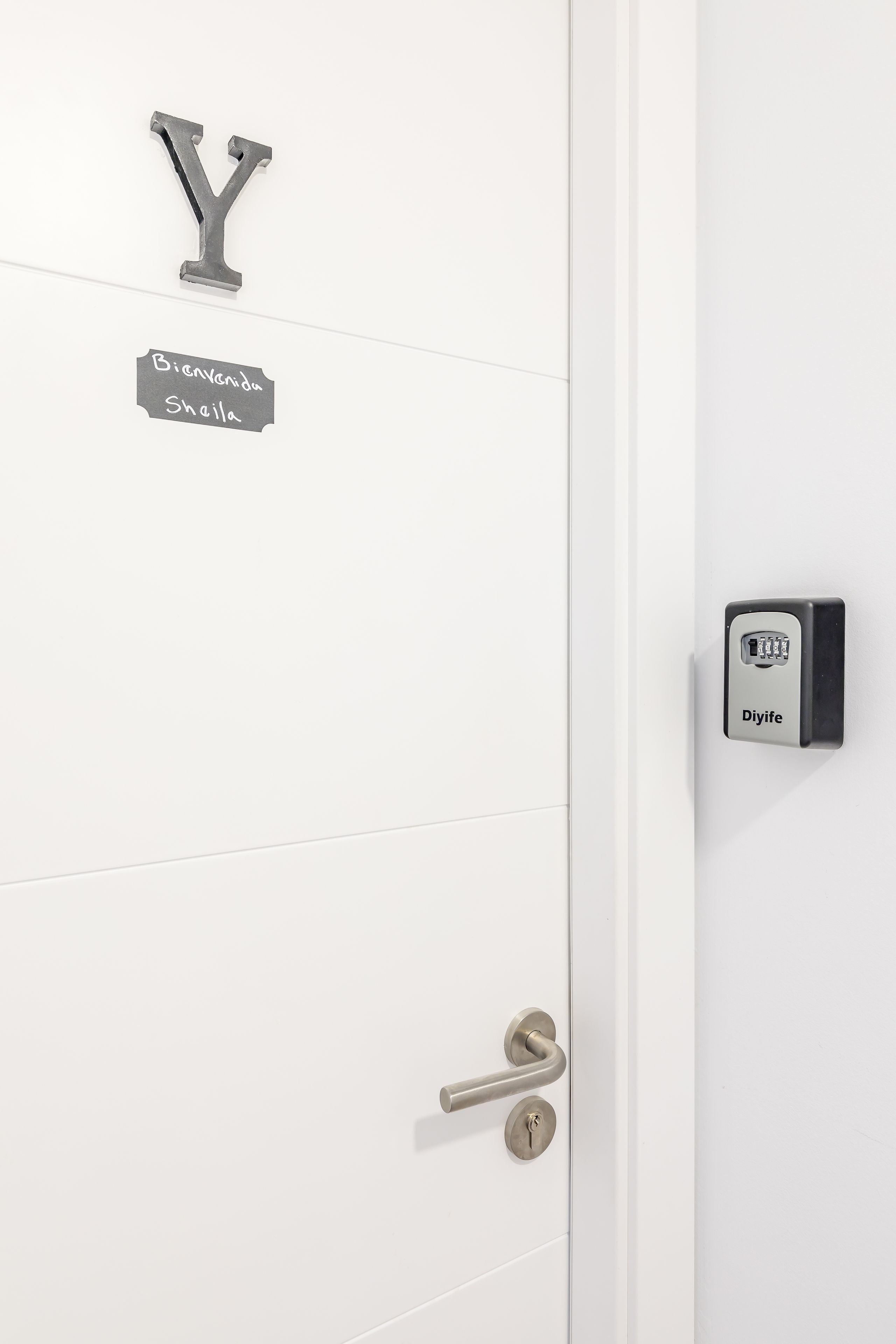 A white door with a metal Y-shaped handle, a metal keyhole, and a Djiife electronic lock.