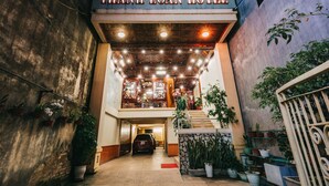 Der Eingang des Thanh Loan Hotels mit einem geparkten Auto davor, Blumentöpfen und einer Treppe, die zu den oberen Stockwerken führt.