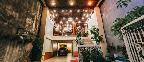 The entrance of Thanh Loan Hotel with a car parked in front, potted plants, and a staircase leading to the upper level.