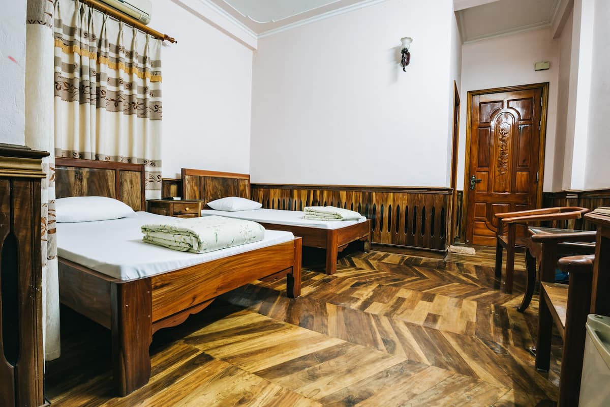 A room with two wooden beds, a wooden chair, a wooden door, and a wooden floor.