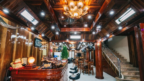 Eine Bar mit Holzwandverkleidung, einem Kronleuchter und einer Treppe zu einer oberen Ebene.