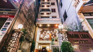 Der Eingang des Thanh Loan Hotels mit einer Steinfassade, mehreren Balkonen und gut beleuchteter Eingangshalle.