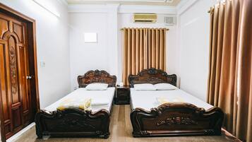 Une chambre d’hôtel avec deux lits en bois, une armoire et un luminaire au plafond.