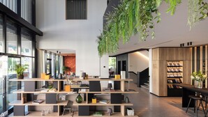 A modern interior with a central shelving unit displaying books and decorative items, a staircase, and a wooden bookshelf with magazines. - Das Altmühltal (Eichstaett)