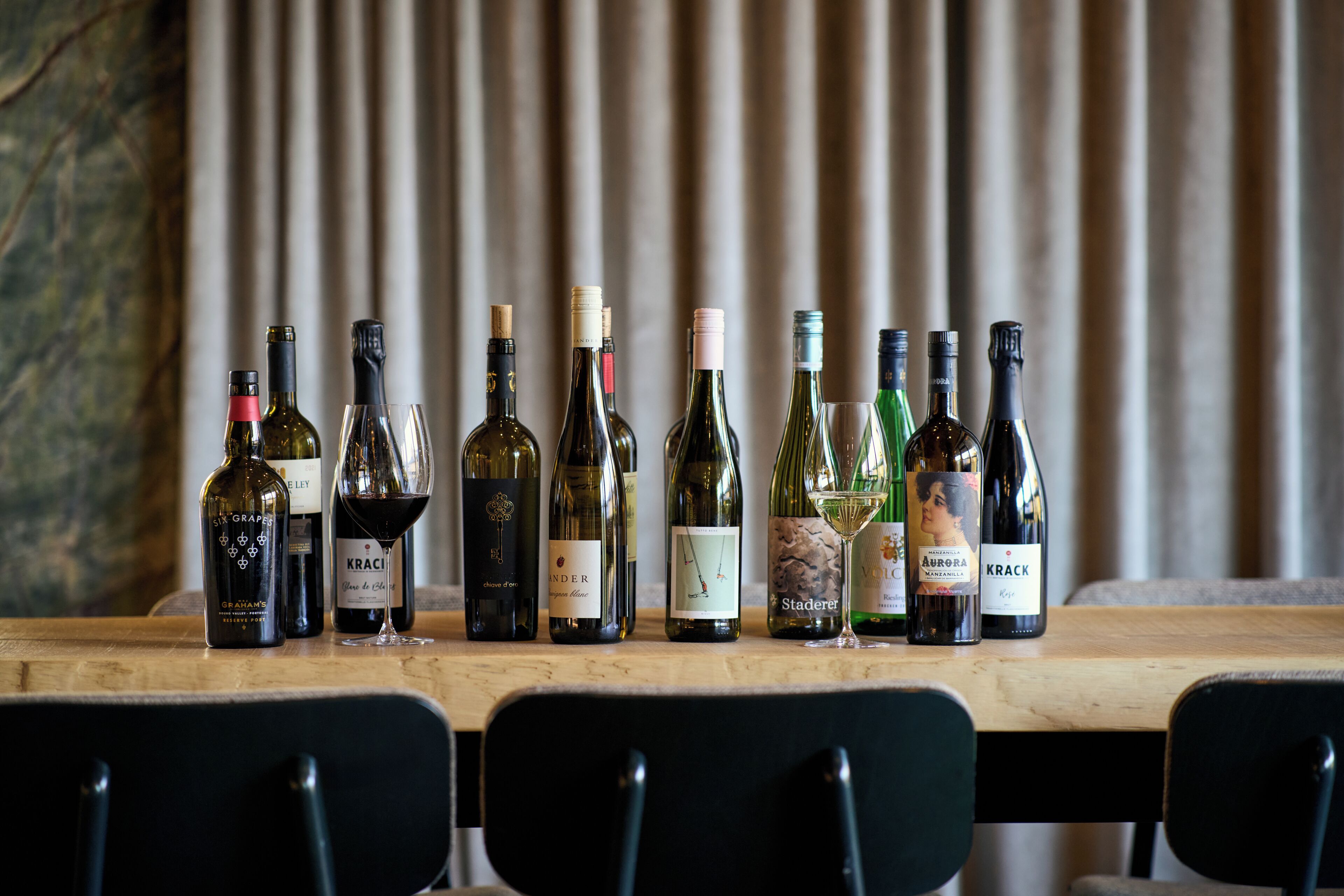 A wooden table with various wine bottles and glasses.