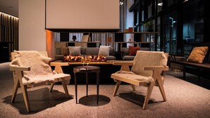A modern interior with two plush chairs, a small table, and a sofa with a fire feature. - Das Altmühltal (Eichstaett)