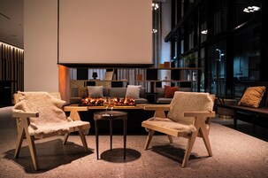Un interior moderno con dos sillones cómodos, una mesita y un sofá con chimenea.