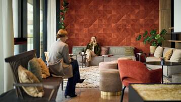 Ein moderner Loungebereich mit Wand in geometrischem Muster, bequemen Sitzgelegenheiten und einem Topf mit Pflanze.