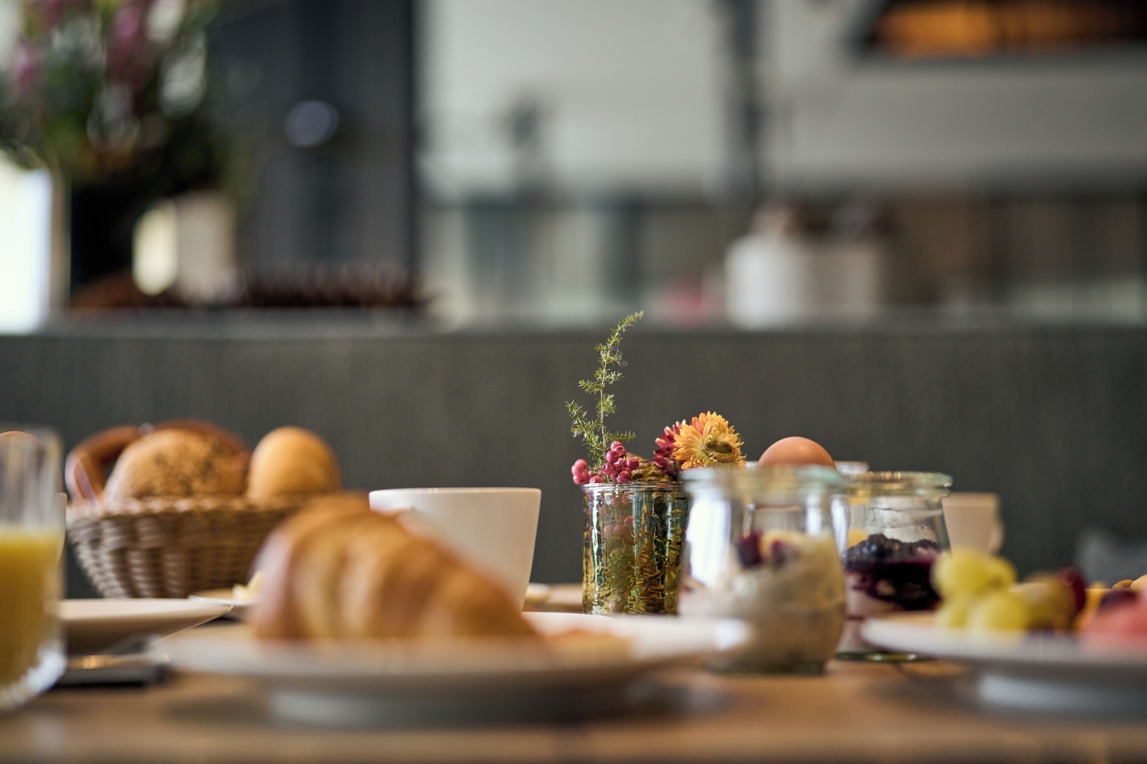 A breakfast table with croissants, a cup, and various fruits and jams.