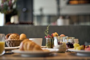 Une table de petit-déjeuner avec des croissants, une tasse et divers fruits et confitures.