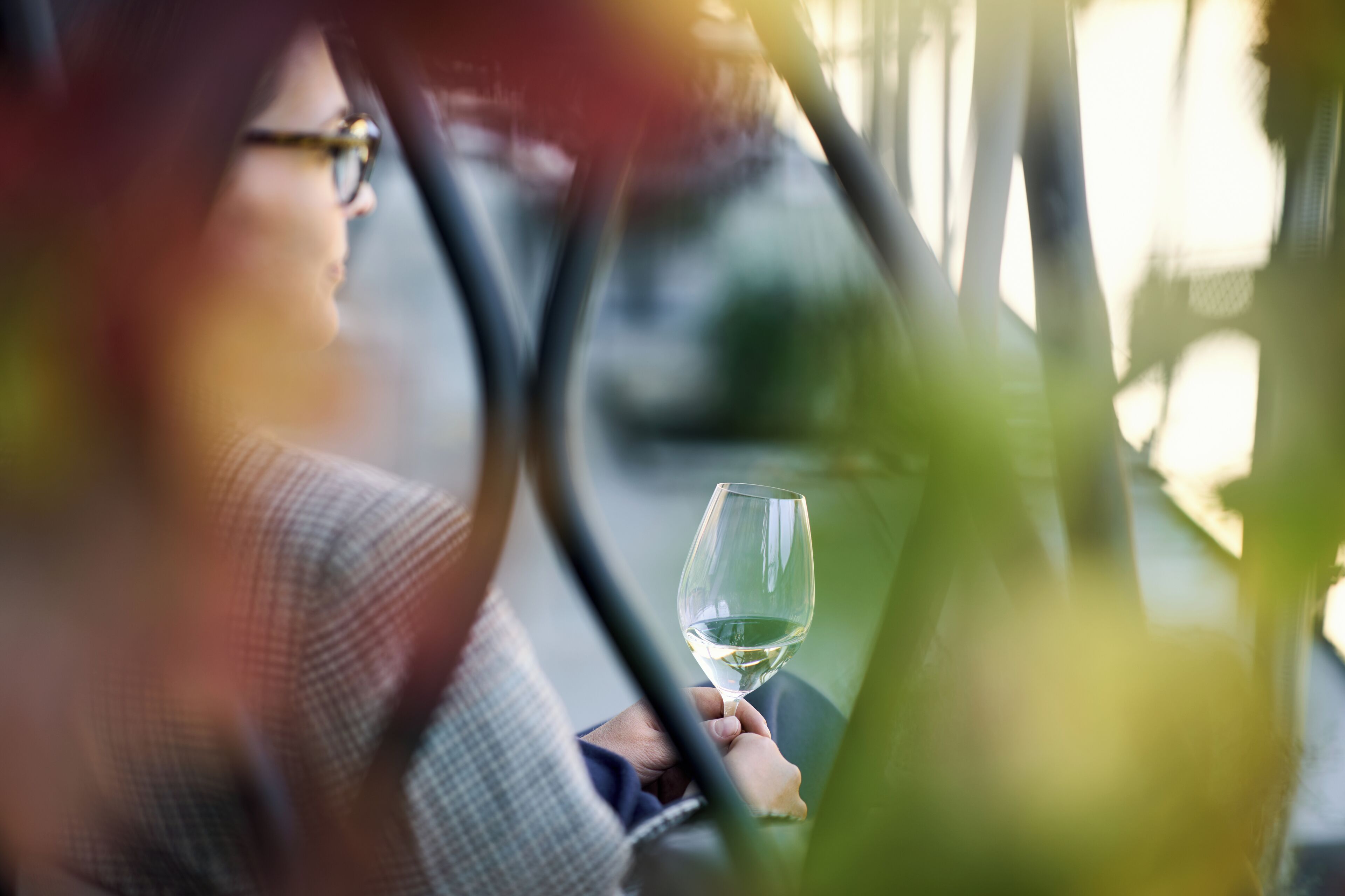 A person holding a wine glass inside a vehicle.