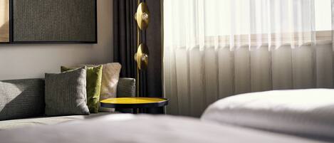 Una habitación de hotel moderna con una cama, una mesita pequeña y una lámpara de pie.