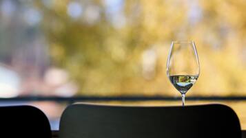 A wine glass on a chair with a blurred autumnal background.