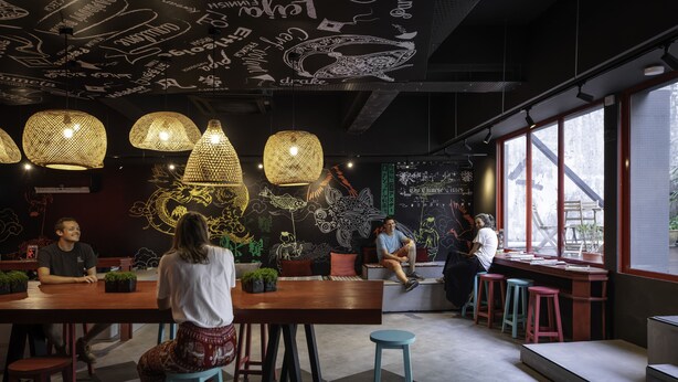 Een modern café met houten tafels en stoelen, decoratieve muurdecoraties en grote ramen.
