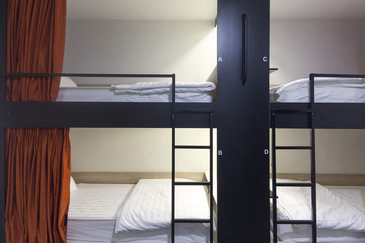 A bunk bed room with two levels, a curtain on the left, and a door with a handle.