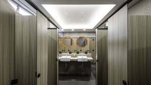 Een moderne badkamer met houten lambrisering, twee wasbakken en decoratieve spiegels.