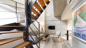 A modern interior with a wooden staircase, a sofa, a coffee table, and a painting on the wall. - Hotel Mei Fukuoka Tenjin (Fukuoka)