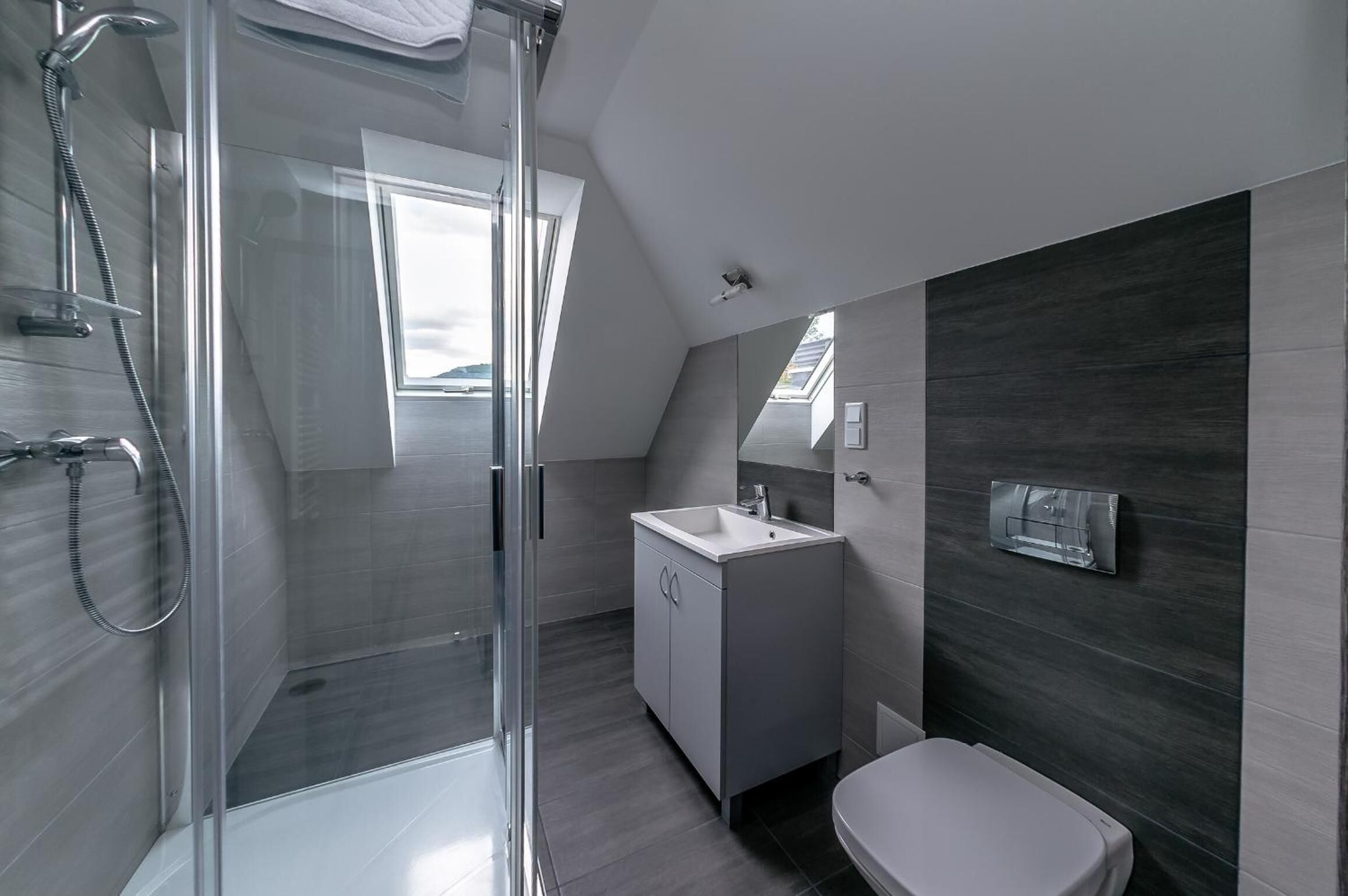 A modern bathroom with a glass shower enclosure, a white sink, and a toilet.