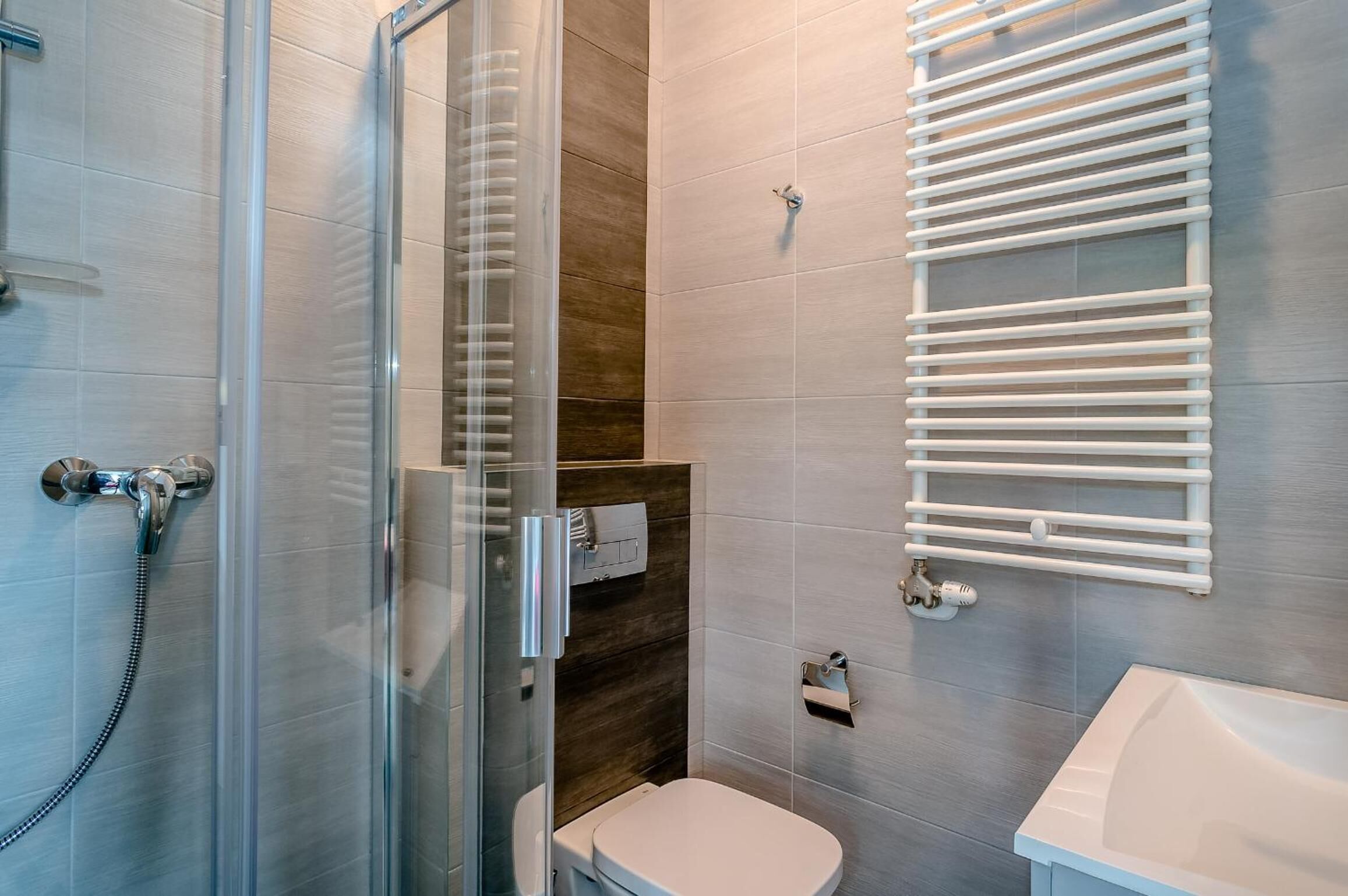 Un baño moderno con cabina de ducha de vidrio, inodoro y lavamanos blanco.
