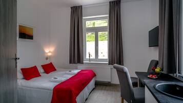 Una camera da letto con un letto, una scrivania, una sedia, una finestra e una TV a parete.