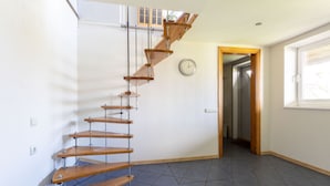 A spiral staircase with wooden steps and metal supports, leading to an upper floor.