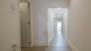 A narrow, well-lit hallway with a tiled floor and white walls. A sign on the left wall requests not to slam the door. - Elba Suites Gaia-Porto (Vila Nova de Gaia)
