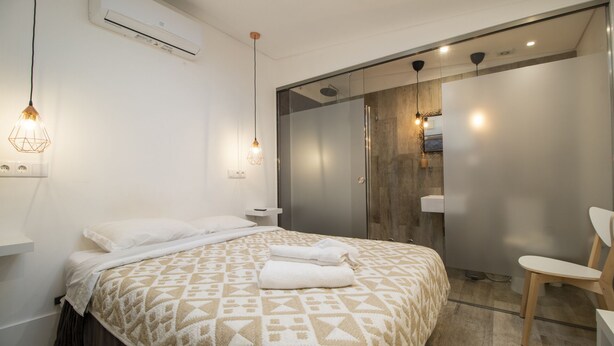 A modern bedroom with a bed, bedside lamps, an air conditioning unit, and a shower area. - Elba Suites Gaia-Porto (Vila Nova de Gaia)