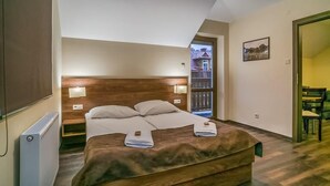 A bedroom with a wooden headboard, a bed with white linens, two bedside lamps, and a view of the outside through a window.