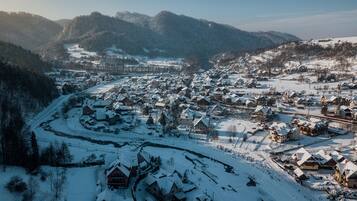 Un pueblo cubierto de nieve con casas tradicionales, un río y montañas al fondo.