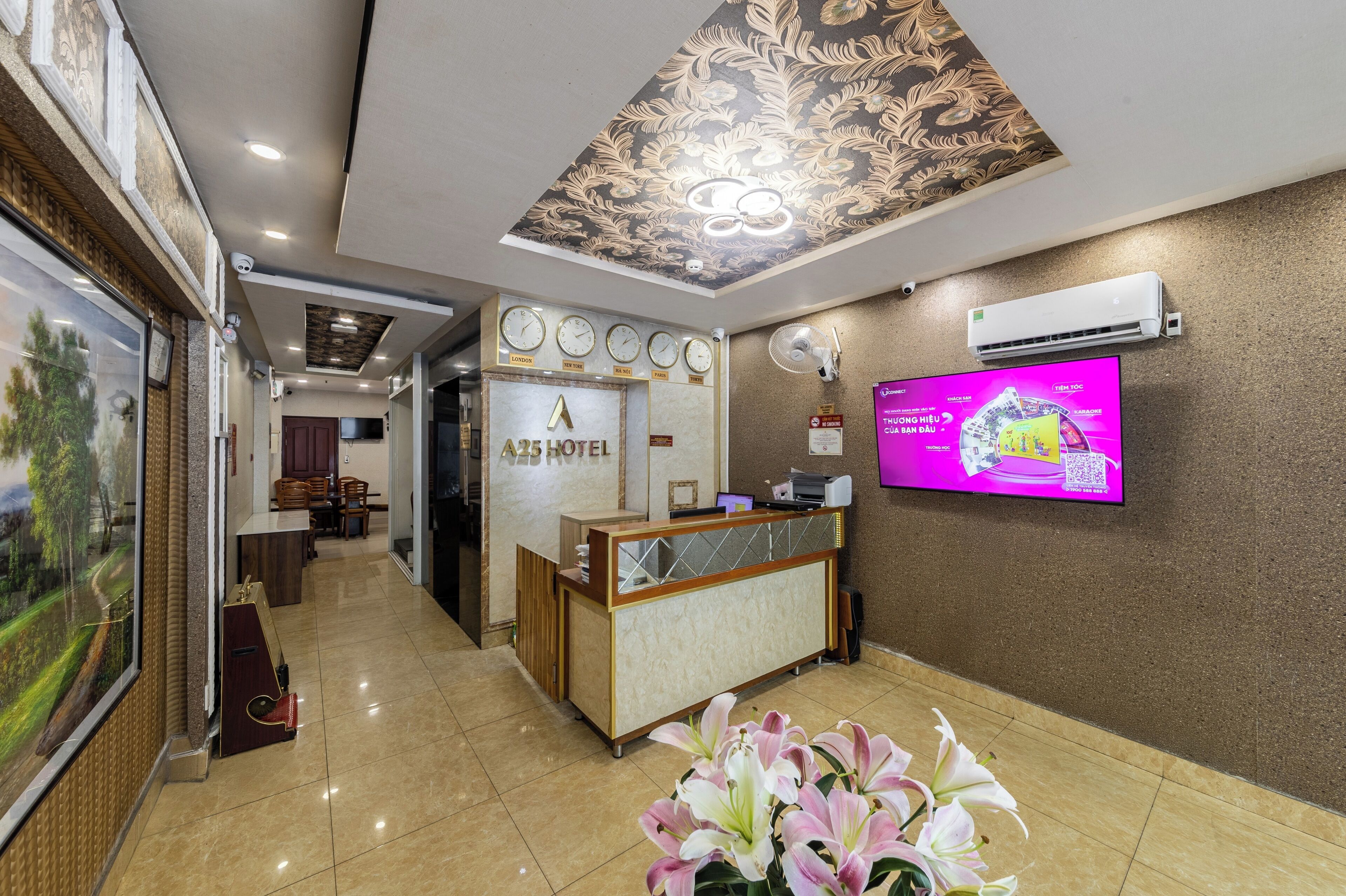 A hotel reception area with a reception desk, a TV screen, and a wall-mounted air conditioner.