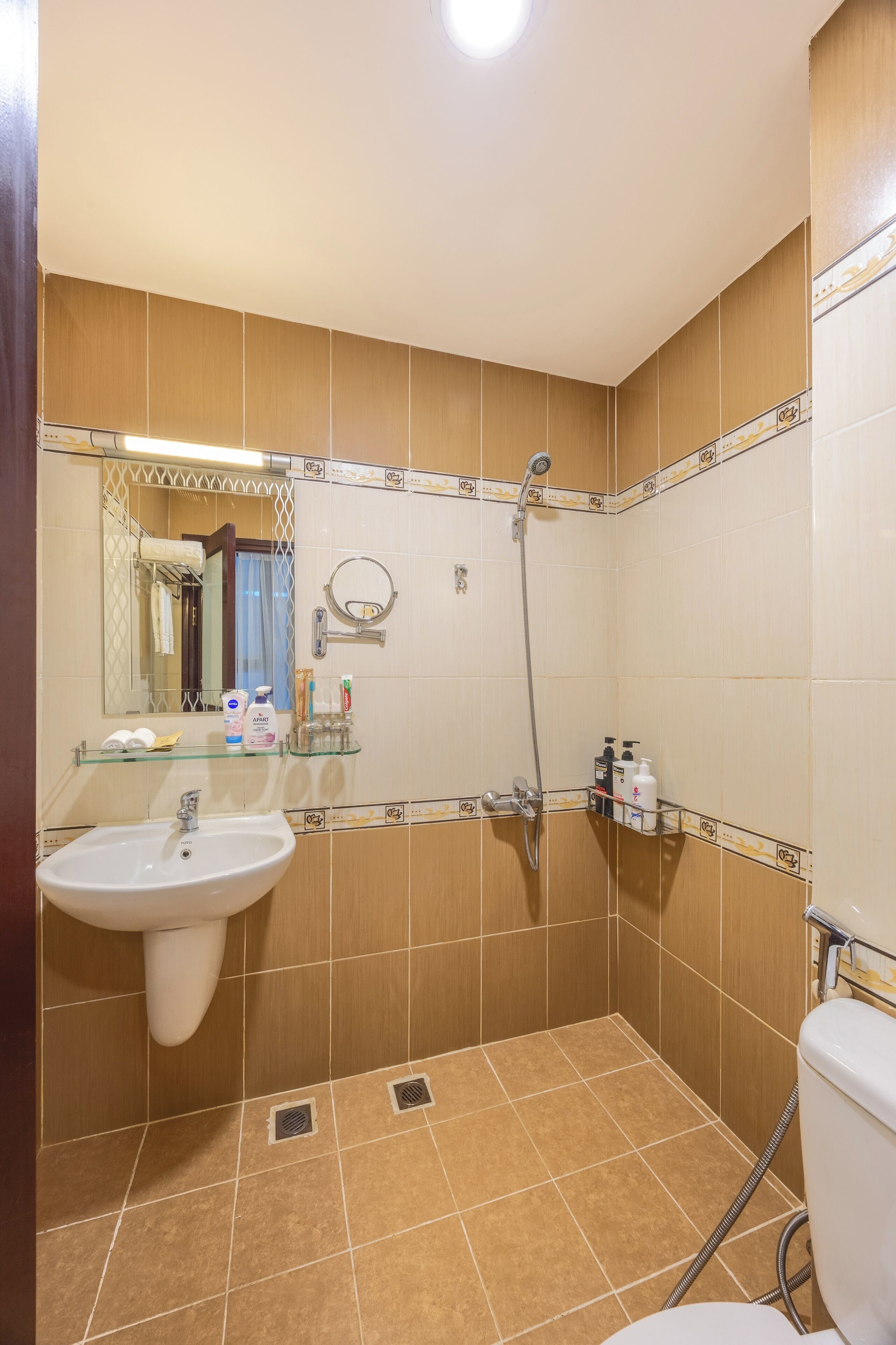 Une salle de bain équipée d’un lavabo, d’un miroir, d’une douche et de toilettes.