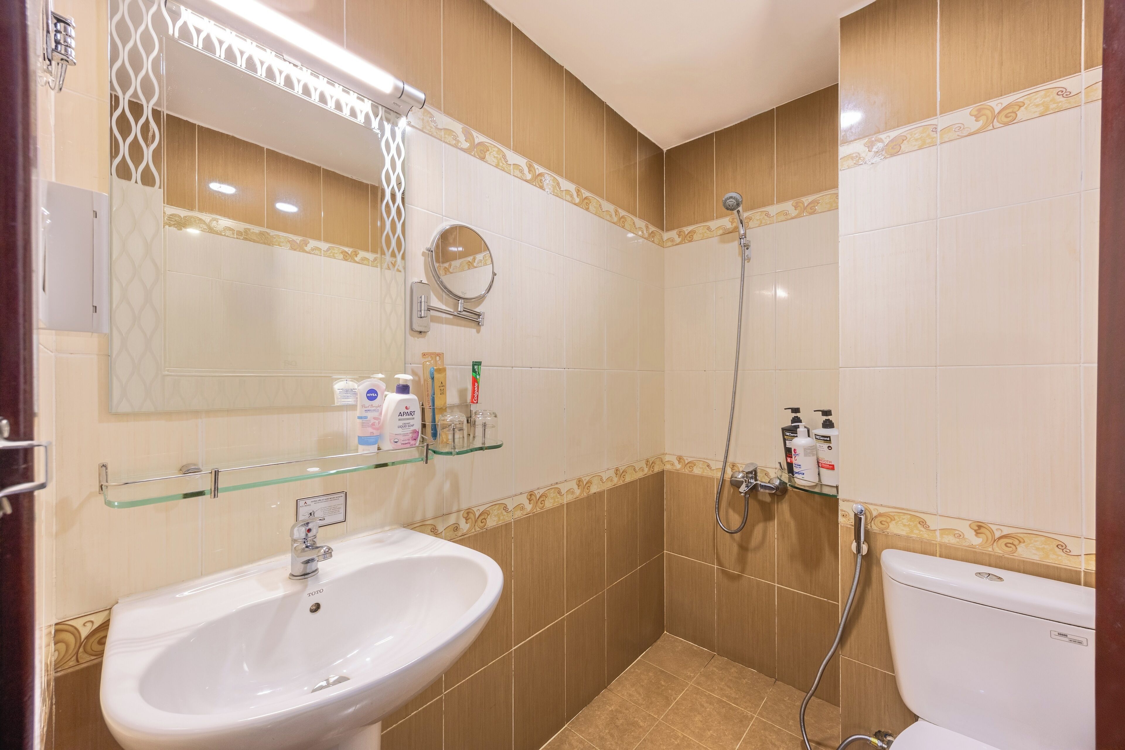 A bathroom with a sink, mirror, shower, and toilet.
