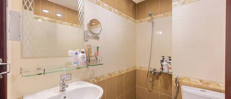 A bathroom with a sink, mirror, shower, and toilet.