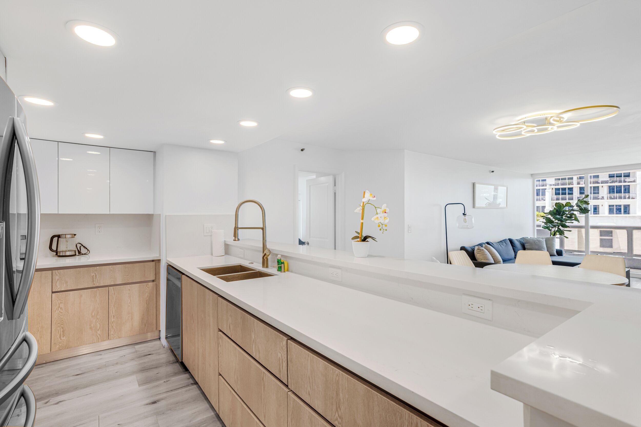 A modern kitchen with a central island, wooden cabinets, and a built-in dishwasher.