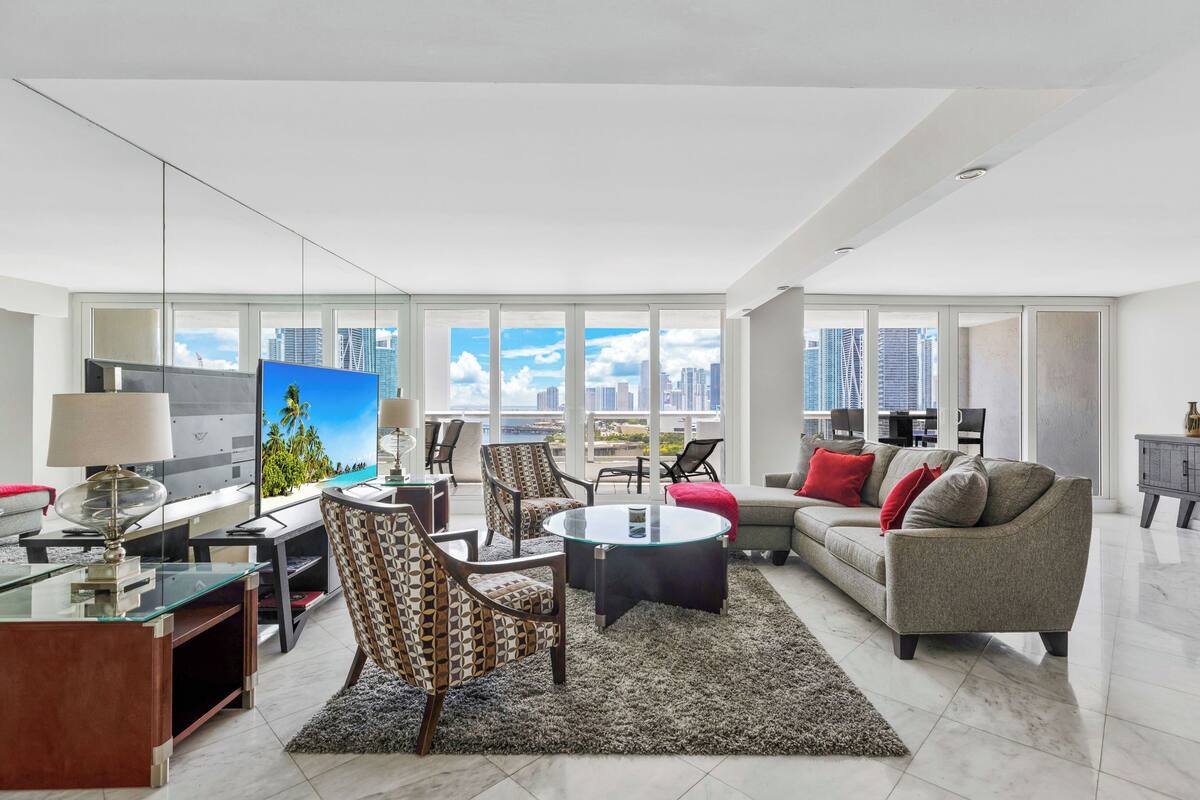 A modern living room with a city view, a flat-screen TV, and contemporary furniture.