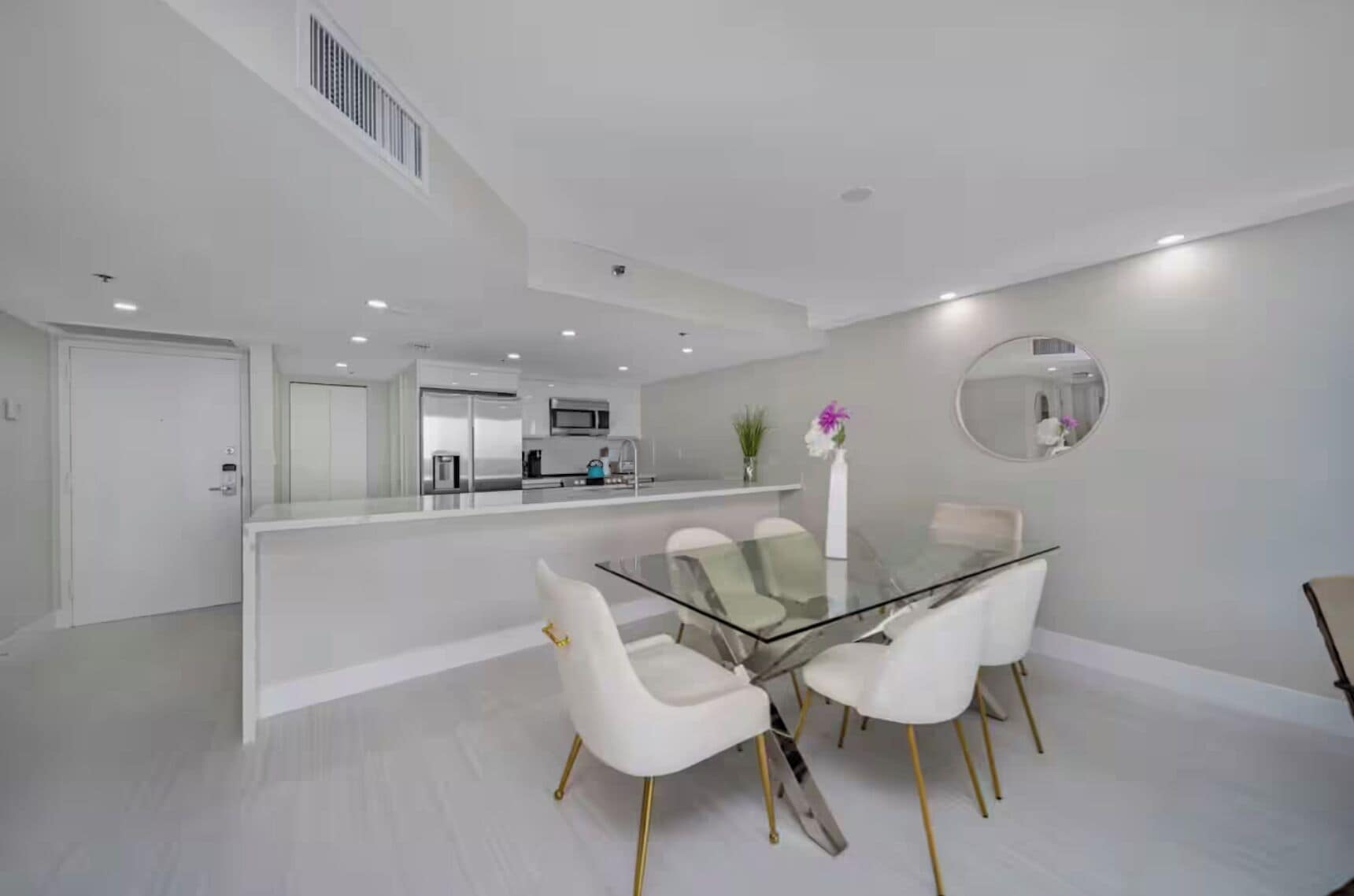 A modern kitchen with white cabinets, a microwave, and a coffee machine.