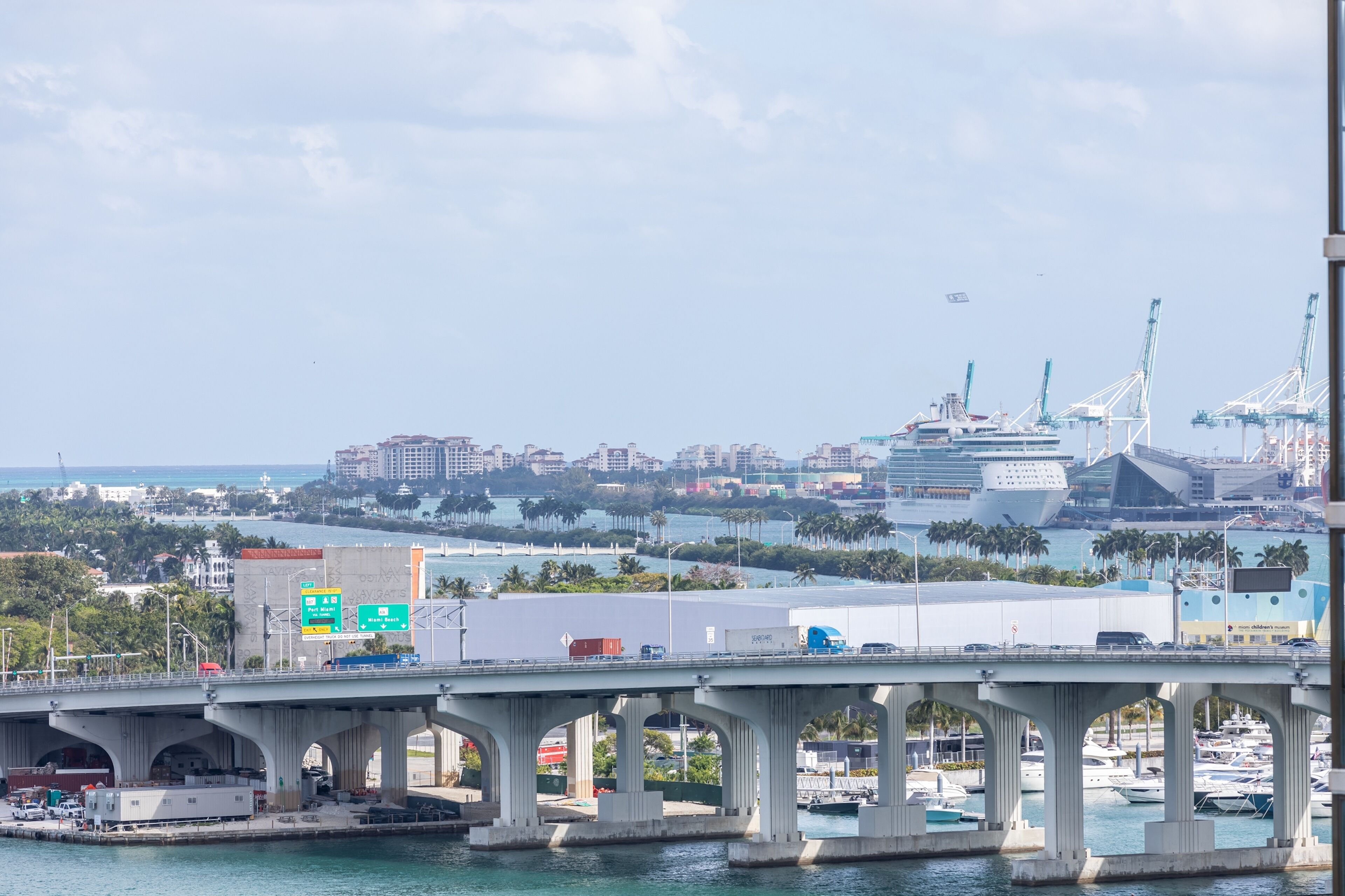 A bridge with multiple arches over a body of water, leading to a marina with boats.